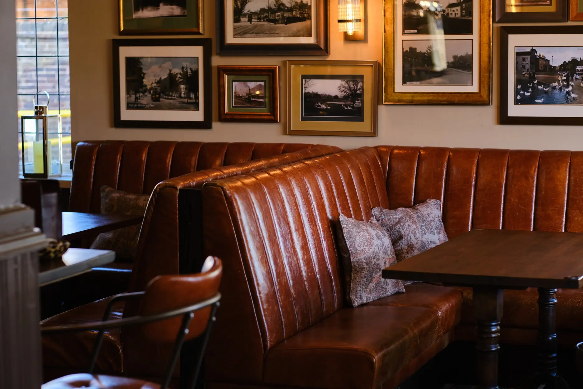 Cosy pub interior with leather booth seating and vintage framed photographs on the wall